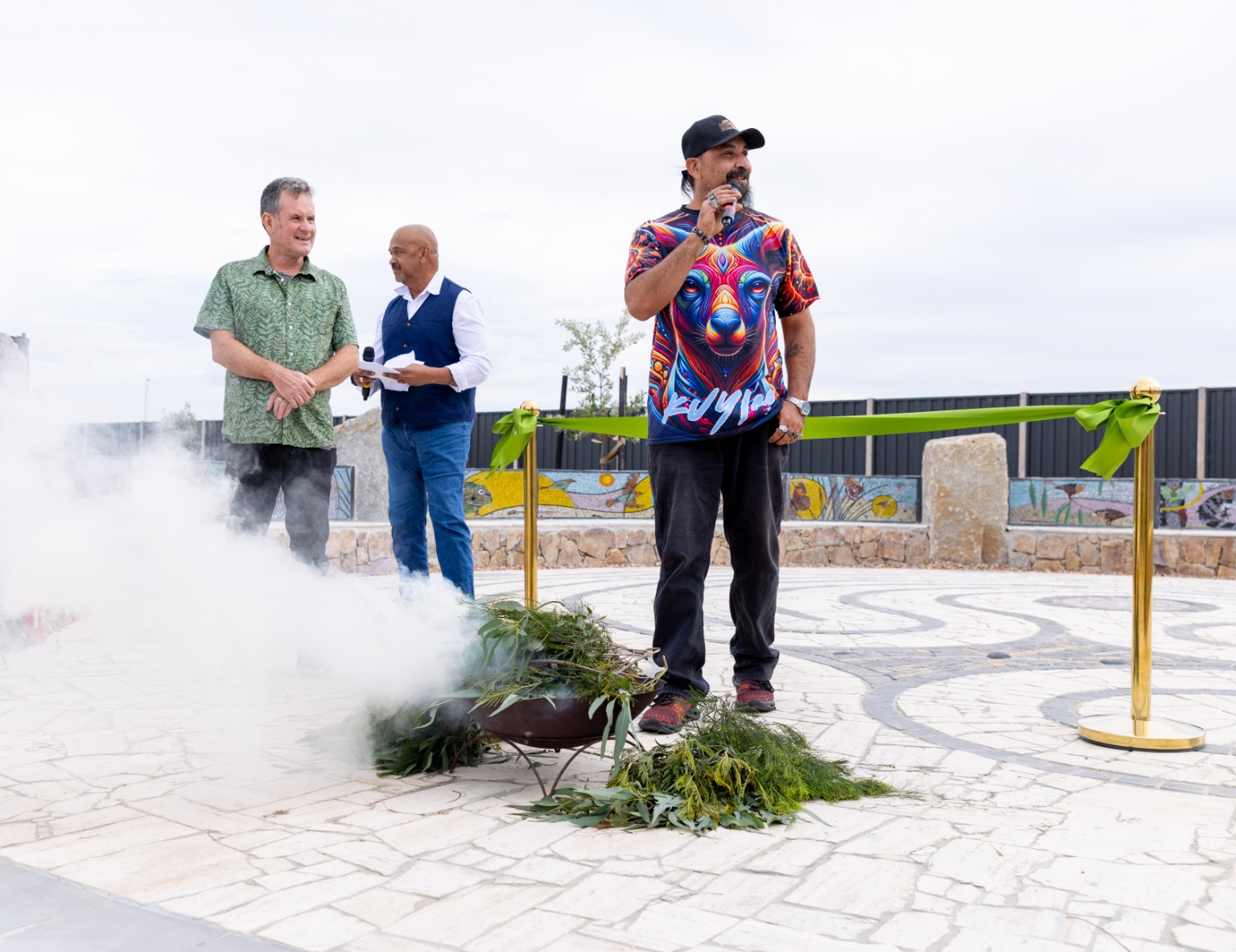 Uncle Mark Brown speaking beside a smoking ceremony at a community gathering